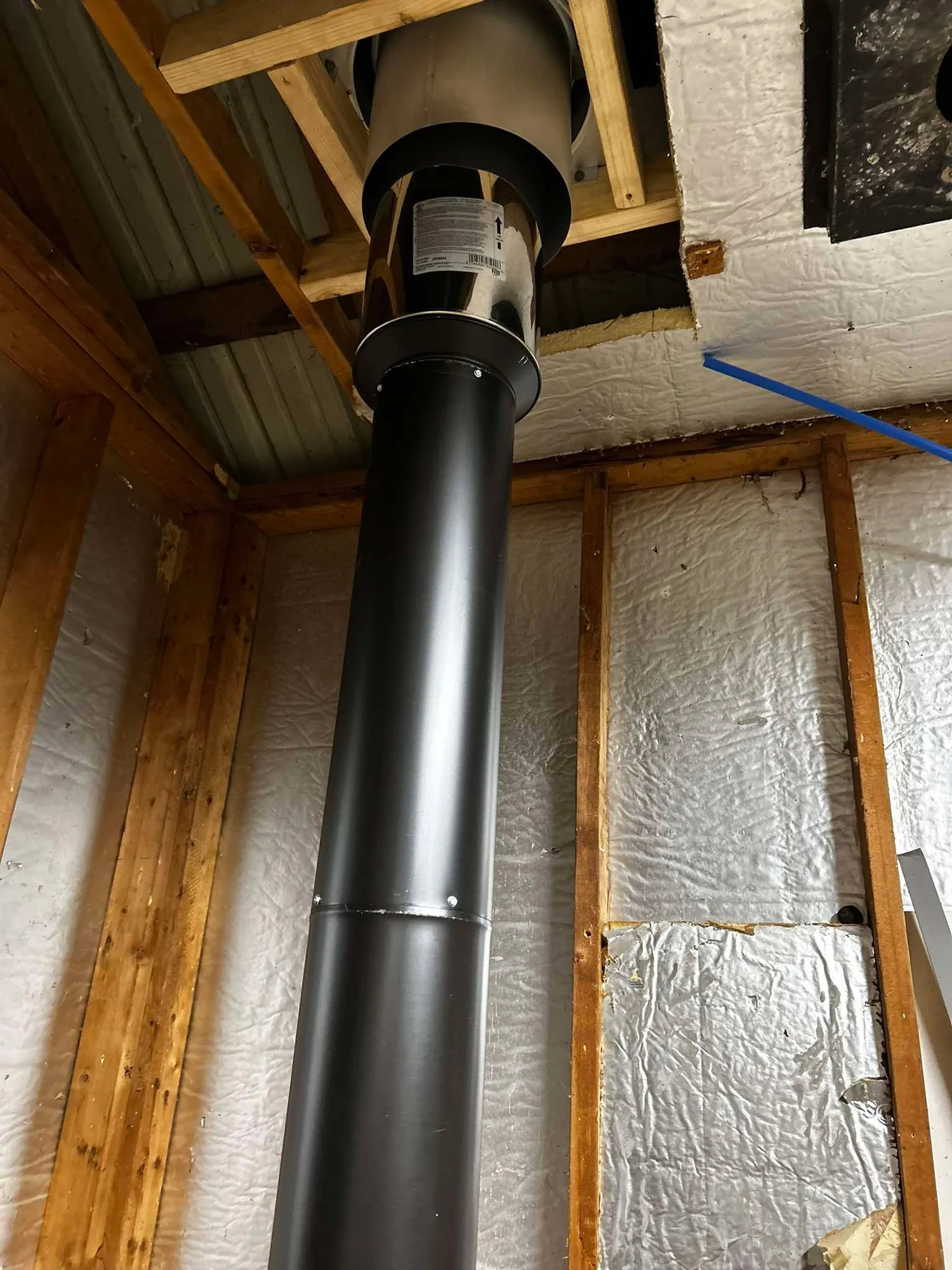 Black stove pipe installation through a framed wall area